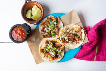 Mexican birria tacos with onion and cilantro on white background