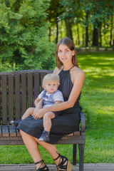 Beautiful young mother with a little son on a bench.