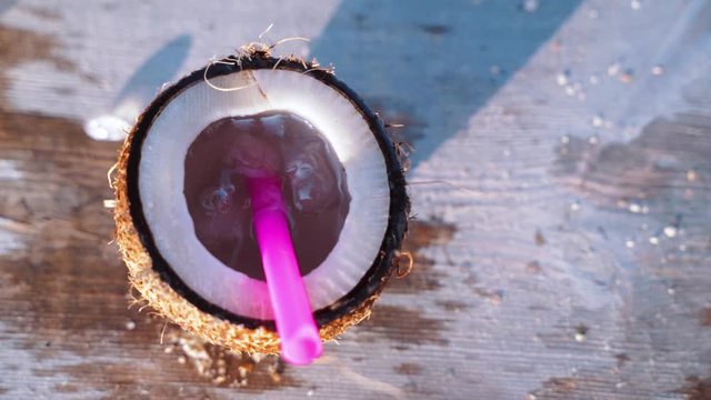 pieces of ice fall from above into a coconut fresh coconut on the table at the beach cafe. Super slow motion shot