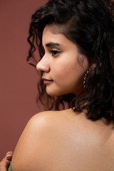 Hispanic woman with curly hair in studio - brunette woman with bare shoulders - natural girl