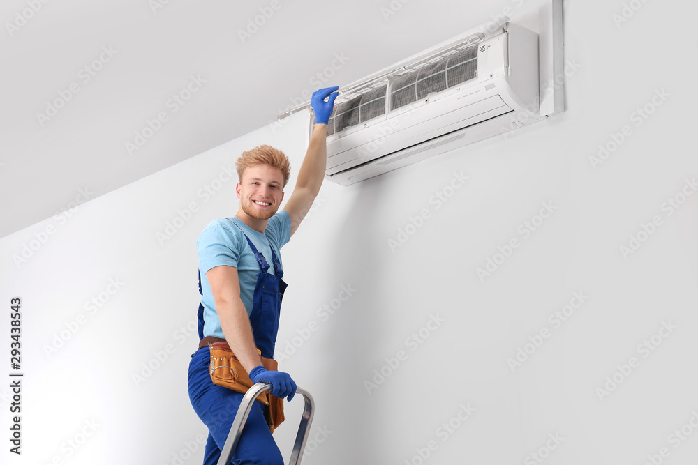 Wall mural professional technician maintaining modern air conditioner indoors