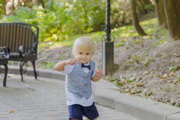 Little boy runs on the asphalt in the park.
