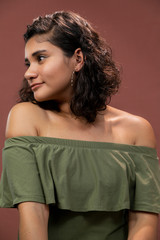 curly hair brunette Hispanic girl with bare shoulders watching the camera smiling- natural young woman- latin woman