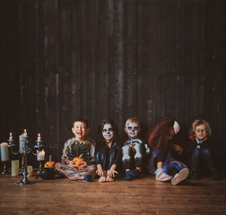 Five little boys and girls are sitting on the floor wearing Halloween costumes.