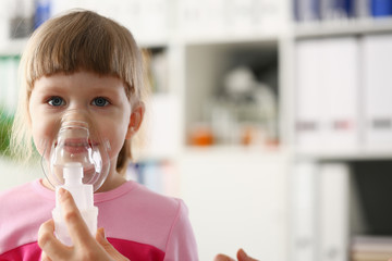 Little girl breathing with inhaler at doctor office portrait