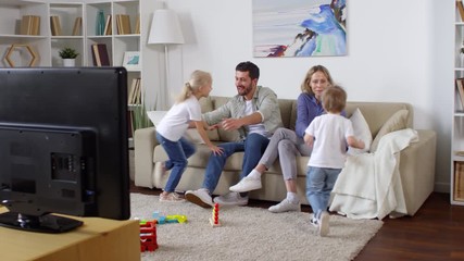 Tracking shot of excited little kids running to their parents sitting on sofa. They are laughing and watching TV together - Powered by Adobe