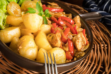 Fried pieces of chicken with red peppers and onions.