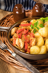 Fried pieces of chicken with red peppers and onions.