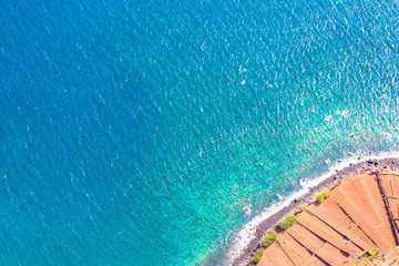 Aerial photography of the Atlantic ocean coast. Stone beach and adjacent fields on the southern coast of Madeira Island in the right bottom corner. Aerial view, seascape. Amazing Portuguese island
