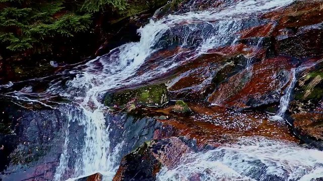 Bergbach, der in einer Schl&uuml;cht &uuml;ber Felsen in einer Mittelgebirgslandschaft herabst&uuml;rzt