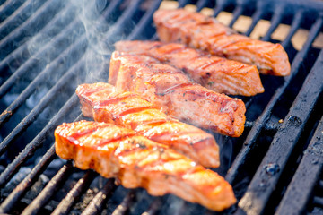Grilled fish steaks. Pieces of salmon are fried over an open fire. Fire and smoke roll over pieces of fish