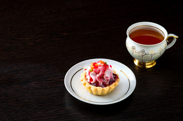 Fototapeta na wymiar Basket-cake with jam on the plate and tea cup on dark background