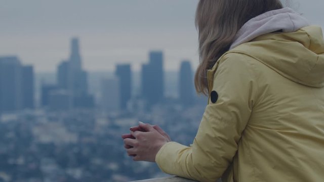 Back view of Caucasian female enjoying the view of of Los Angeles Downtown from Griffith observatory, all brand names and logos removed. 4K UHD