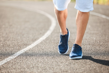 Sporty young man running at the stadium, closeup