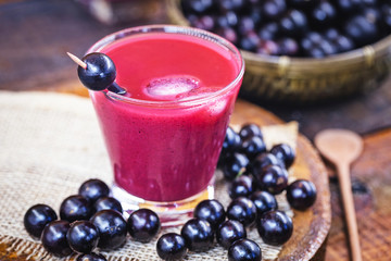 Glass of jabuticaba juice, seen from above. with various fruits around. Brazilian exotic fruit juice.