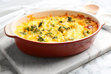 Tasty broccoli casserole in baking dish on white marble table