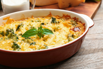 Tasty broccoli casserole in baking dish on wooden table, closeup