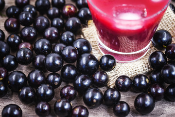 Glass of jabuticaba juice, seen from above. with various fruits around. Brazilian exotic fruit juice.