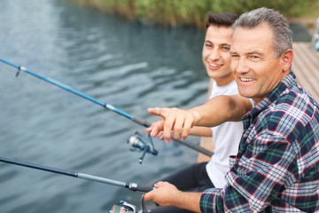 Young man and his father fishing on river