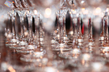 A large number of glasses are on the bar. Out of focus. Blurred background.