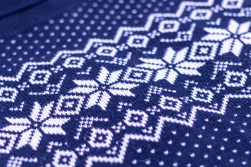 Warm Christmas blue sweater with snowflakes. Vintage Scandinavian Woolen Jumper Pattern. Closeup. Background. Knitting pattern with snowflakes.