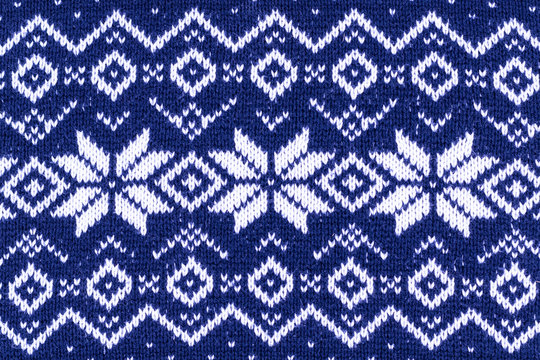 Warm Christmas blue sweater with snowflakes. Vintage Scandinavian Woolen Jumper Pattern. Closeup. Background. Knitting pattern with snowflakes.