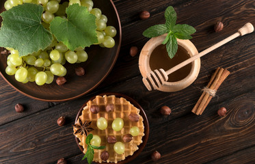 Fototapeta na wymiar waffles with honey and grapes on a wooden background