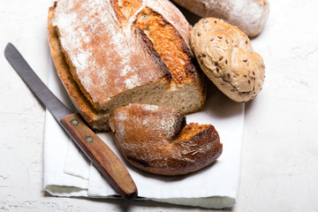 Tasty dark bread and buns  on white background, copy space. Bakery products, wholemeal bread and brown whole wheat buns