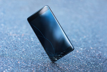 Mobile phone falls and hits the asphalt, broken glass display. Broken smartphone and touchscreen....