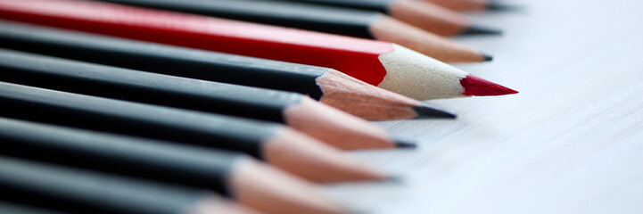 Red pencil standing out from crowd of plenty identical black fellows. Leadership uniqueness...