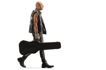 Musician in leather clothes walking with a guitar case