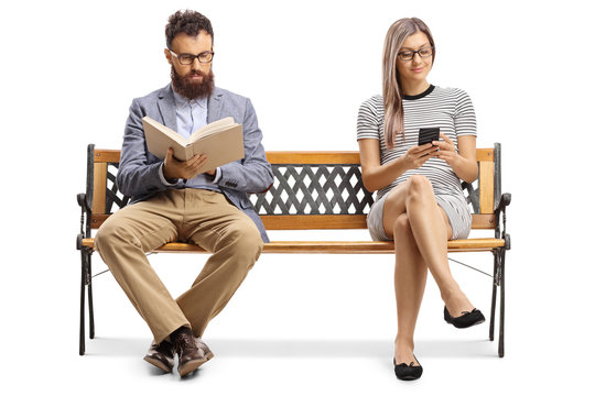 Man reading a book and woman sitting on a bench and typiing on a mobile phone