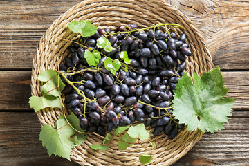 Plate with tasty sweet grapes on wooden table