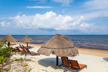 Caribbean Sea with Beach chairs and grass umbrellas in Cancun