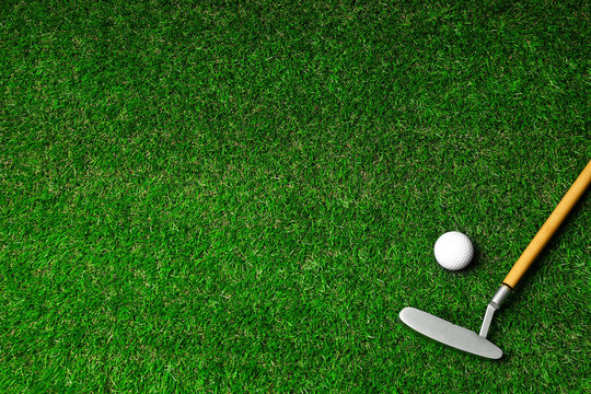 Golf ball and club on green course, flat lay. Space for text