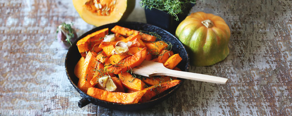 Pumpkin slices with thyme and garlic in a pan. Healthy autumn food. Vegan lunch.