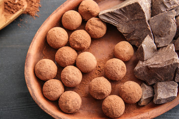 Plate with tasty sweet truffles and chocolate on table