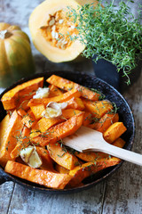 Pumpkin slices with thyme and garlic in a pan. Healthy autumn food. Vegan lunch.