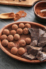 Plate with tasty sweet truffles and chocolate on table