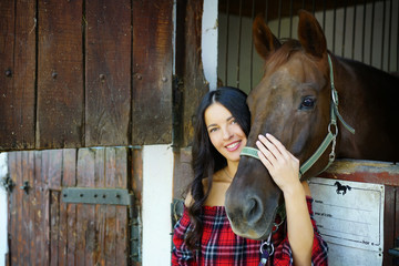 Fototapeta na wymiar Beautiful girl hugging her brown horse in a barn 
