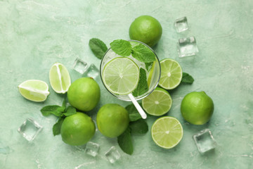 Glass of fresh mojito with lime on color background