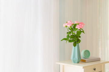 Beautiful rose flowers in vase on table near window