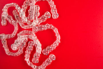 Top view of invisalign braces or invisible retainers on red background, new orthodontic equipment