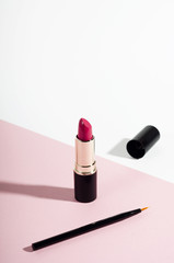 Fashion red lipstick and pencil top view composition. Beauty industry product concept. Glamorous...