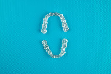 Top view of invisalign braces or invisible retainers on blue background, new orthodontic equipment