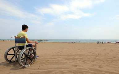 Obraz premium young boy on a wheelchair looks at the sea