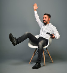 Emotionally play the game console. Man holding a joystick and gesticulating with legs and arms....