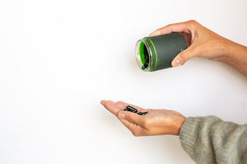 Woman pouring green vitamin supplements in jar