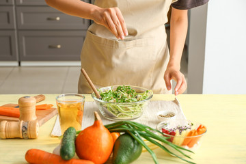Woman preparing tasty vegetable salad in kitchen, closeup