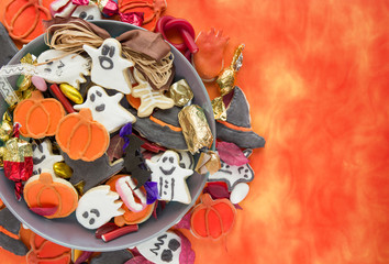 Halloween Jack o Lantern candy bowl with candy and halloween cookies Trick or Treat on orange background